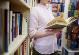 mulher segurando livro aberto em uma biblioteca