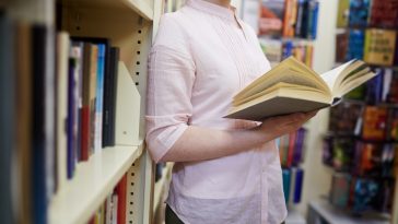 mulher segurando livro aberto em uma biblioteca