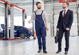 Homem de negócios conversando com funcionário em fábrica de automóveis
