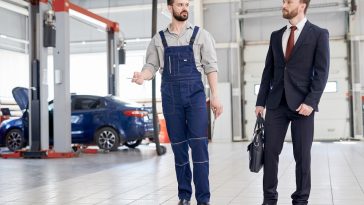 Homem de negócios conversando com funcionário em fábrica de automóveis