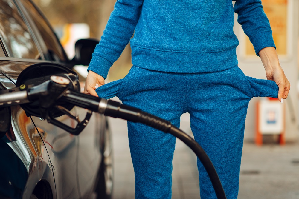 mulher abastecendo gasolina e mostrando os dois bolsos vazios