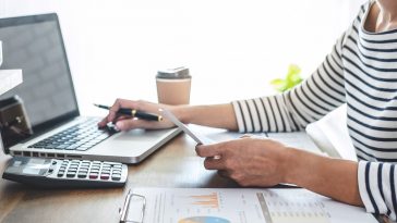 moça sentada em frente ao notebook com uma planilha de resultados