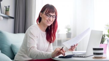 mulher sorridente calculando suas finanças