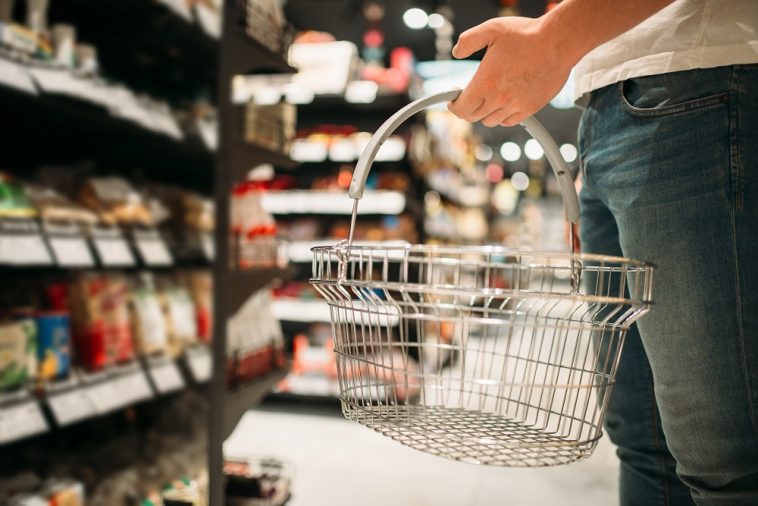 homem com cesta de compras vazia na mão olhando para a prateleira no supermercado