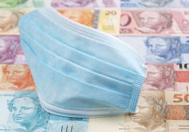 cédulas de dinheiro ao fundo e uma máscara utilizada na pandemia mais a frente