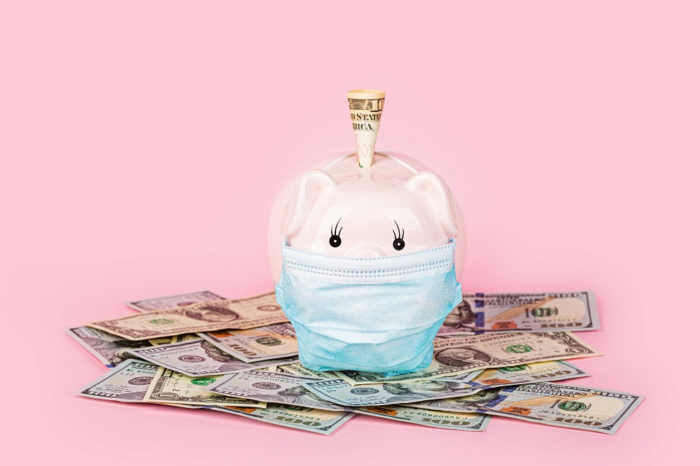 cofre de porquinho rosa com máscara em volta de dinheiro em dólar