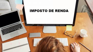 mulher mexendo no computador escrito imposto de renda