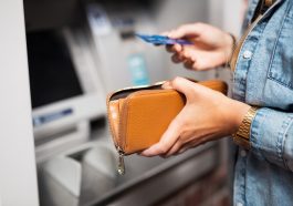mulher com cartão em frente ao caixa eletrônico