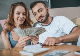 casal fazendo as contas para o orçamento familiar e contando o dinheiro que está sobrando