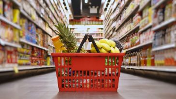 cesta básica com algumas frutas no chão de um supermercado, simbolizando o preço da cesta básica em BH