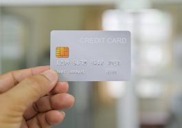Mão mostrando cartão de crédito branco em um fundo desfocado