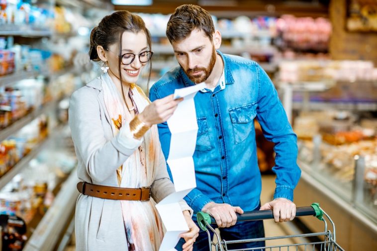 casal conferindo compras no supermercado com CPF na nota fiscal