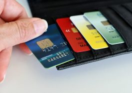 mão de mulher pegando um cartão de crédito para negativados em sua carteira, com outros três cartões