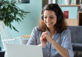 mulher assistindo palestra online sobre vagas de estágio, com aparência feliz