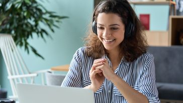 mulher assistindo palestra online sobre vagas de estágio, com aparência feliz