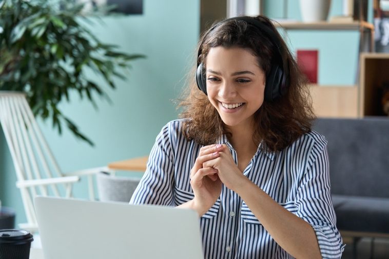 mulher assistindo palestra online sobre vagas de estágio, com aparência feliz