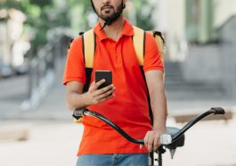 entregador acessando o aplicativo no celular, mostrando que trabalha para fazer uma renda extra