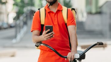 entregador acessando o aplicativo no celular, mostrando que trabalha para fazer uma renda extra