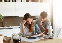 Casal de família triste percebendo suas dívidas com cheque especial, olhando atentamente em documentos, calculando sua família