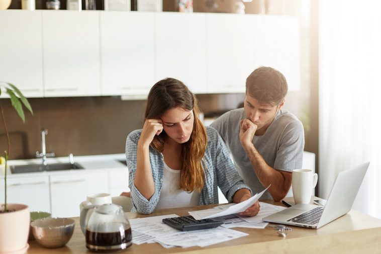 Casal de família triste percebendo suas dívidas com cheque especial, olhando atentamente em documentos, calculando sua família