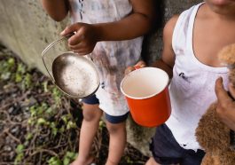Visão recortada de crianças afro-americanas desabrigadas segurando copo