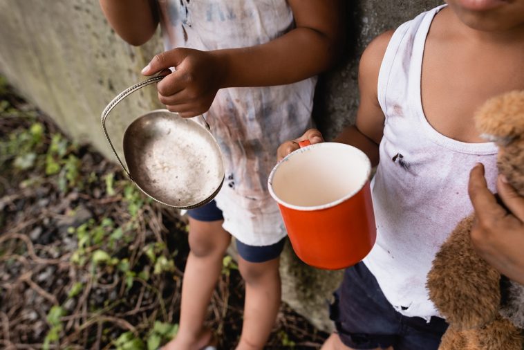 Visão recortada de crianças afro-americanas desabrigadas segurando copo