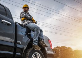 homem mecânico freelancer sentado em cima de um capô de carro com algumas ferramentas na mão