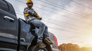 homem mecânico freelancer sentado em cima de um capô de carro com algumas ferramentas na mão