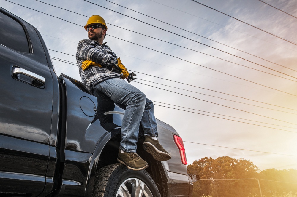 homem mecânico freelancer sentado em cima de um capô de carro com algumas ferramentas na mão