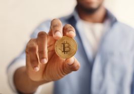 Bitcoin dourado em closeup de mão homem afro-americano