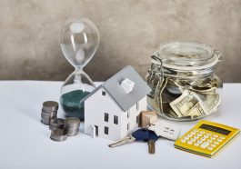 modelo de casa com ampulheta, calculadora, dinheiro e chaves, conceito imobiliário