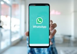 homem desfocado ao fundo segurando um celular mostrando o aplicativo do WhatsApp que agora faz envio de dinheiro