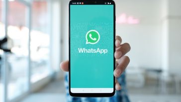 homem desfocado ao fundo segurando um celular mostrando o aplicativo do WhatsApp que agora faz envio de dinheiro