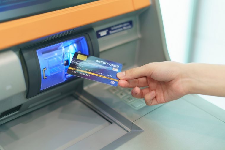 mão de mulher inserindo um cartão de crédito em um caixa eletrônico, para ilustrar o saque com cartão de crédito