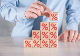 mão do empresário pega um bloco de cubo de madeira representando, mostrado o ícone do símbolo de porcentagem. conceito de taxas financeiras e hipotecas de taxa de juros Selic