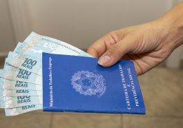 carteira de trabalho com dinheiro notas de cem reais dentro demostrando as novas vagas de emprego no Brasil