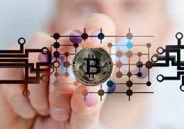 mão segurando uma Bitcoin ao fundo