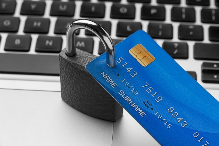cadeado de bloqueio com cartão de crédito em cima do laptop simbolizando a proteção de um seguro de cartão de crédito