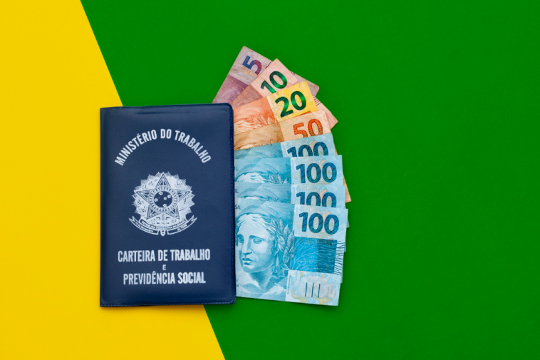 fundo verde e amarelo com carteira de trabalho e notas de dinheiro em real dentro simbolizando o pagamento do 13° salário décimo