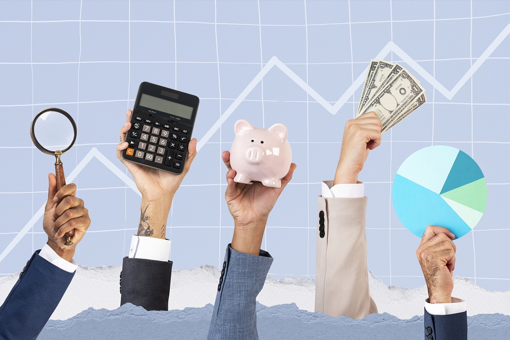 mãos segurando acessórios financeiros, como calculadora, lupa, cofrinho, nota de dinheiro, simbolizando a nova alta da Selic e o impacto no rendimento da poupança