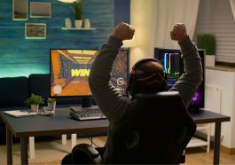 Jogador de videogame levantando as mãos após vencer a competição e assim ganhar gamecoins, criptomoedas de jogos