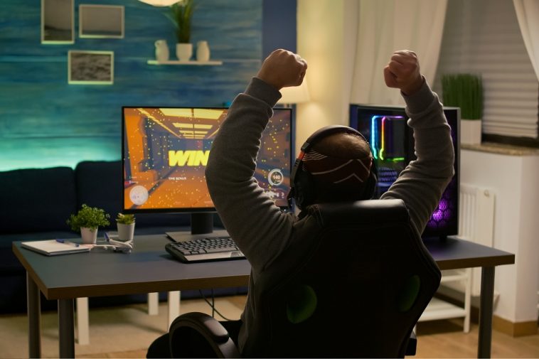 Jogador de videogame levantando as mãos após vencer a competição e assim ganhar gamecoins, criptomoedas de jogos