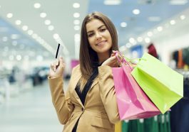 Jovem mulher com cartão de crédito e sacola de compras