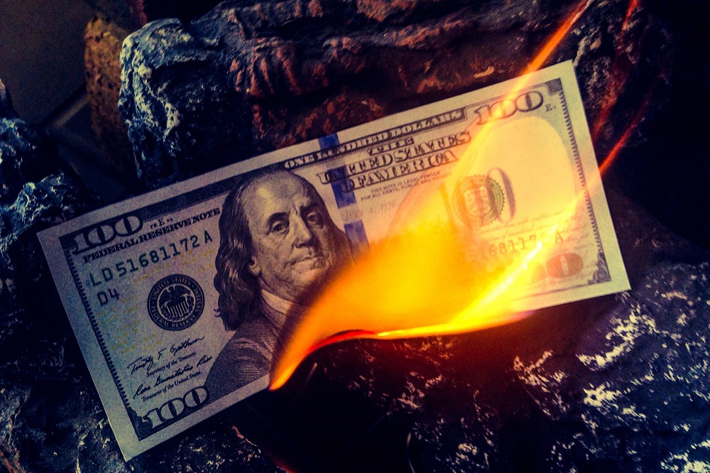 nota de dólar queimando simbolizando formas de proteger seu dinheiro em ano de eleição
