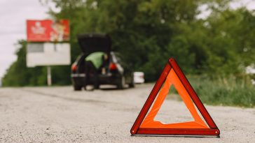 Carro com problemas e um triângulo vermelho para avisar outros usuários da estrada