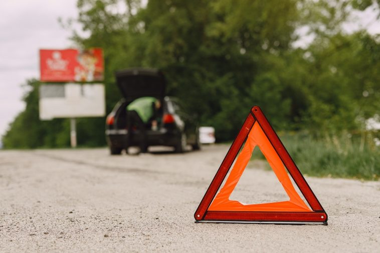 Carro com problemas e um triângulo vermelho para avisar outros usuários da estrada