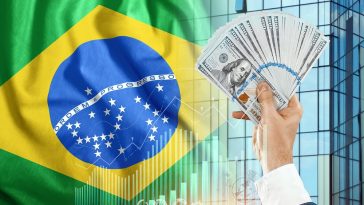 Dinheiro na mão de um homem no contexto da bandeira do brasil simulando o pagamento de impostos obrigatórios no Brasil para pessoas físicas e empresas