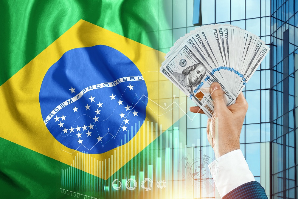 Dinheiro na mão de um homem no contexto da bandeira do brasil simulando o pagamento de impostos obrigatórios no Brasil para pessoas físicas e empresas