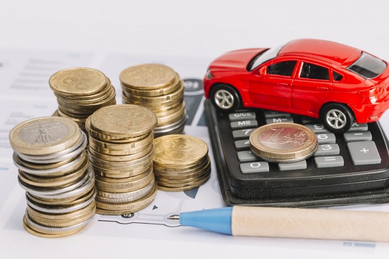 Pilha de moedas; calculadora; carro de brinquedo e caneta no modelo simulando o IPVA mais caro em 2022