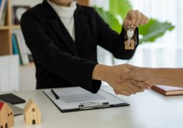 O representante de vendas aperta as mãos e entrega as chaves para os novos proprietários representado o aumento na procura de consórcio imobiliário no Brasil em 2021